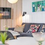 A living room with sofa, cushions, TV, and wall art.