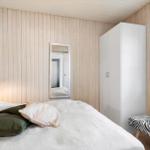 Bedroom with bed, wardrobe, and window. Wooden wall and zebra-patterned bench.