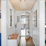 Hallway with wooden floor, white walls, and door to balcony. Bedrooms on left and right.