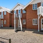 Red brick houses with white stairs and windows. Gravel ground and wooden railings.