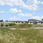 Green lawn with playground and vacation houses in the background.