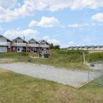 Green outdoor area with sandbox, swing, and soccer goal in front of holiday homes.