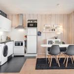 Kitchen with dining area, white cabinets, black countertop, and wooden wall.
