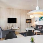Living room with sofa, TV, and dining table. Wooden wall and ceiling.
