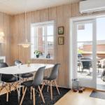 Dining room with white table, black chairs, and wooden walls. Glass door leads to the terrace.