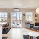 Living and dining area with wooden walls, windows, and door to outdoor area.