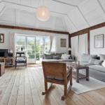 Wohnzimmer mit Holzboden, grauem Sofa und Schiebetür zum Garten.