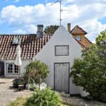 Wohnhaus mit Terrasse, Garten und Terrakottadach unter blauem Himmel.