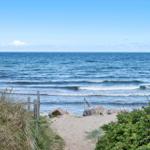 Sandweg führt zum Strand mit Blick auf das offene Meer.