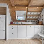 Küche mit weißer Arbeitsplatte, Holzdecke und Küchenzeile