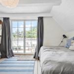 Schlafzimmer mit Dachschräge, Bett, Fenster und Holzboden.