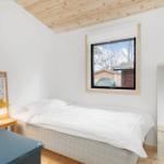 Ein Schlafzimmer mit Bett, Fenster und Spiegel. Holzdecke und Boden.