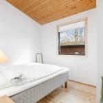 Schlafzimmer mit Bett, Lampe und Fenster. Holzdecke und Boden.