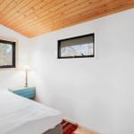 Schlafzimmer mit Holzdecke, zwei Fenstern und einem Bett mit weißer Bettwäsche.