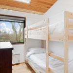 Zimmer mit Doppelstockbett, Fenster und Holzdecke.