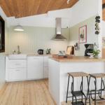 Küche mit Holzdecke, weißen Schränken und Holzwerkzeugen an der Wand.