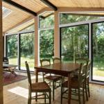 Esszimmer mit Holztisch, Stühlen und großen Fenstern zum Garten