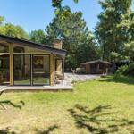 Moderne Holzhütte mit großem Glasbereich und Terrasse im Grünen.