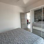 Schlafzimmer mit Bett, Spiegelschrank und Tür zum Flur.