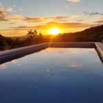 Pool mit Blick auf Sonnenuntergang und Hügel mit Windkraftanlagen.