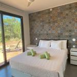Schlafzimmer mit Bett, Decke, Nachttischen und Flügeltür zum Balkon.