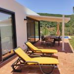 Terrasse mit Liegen, Tisch und Blick auf Pool und Hügel.