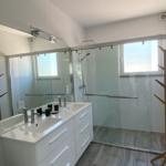 Badezimmer mit Dusche, Waschbecken und Spiegel.