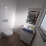 Badezimmer mit Toilette, Waschbecken und Spiegel an der Wand.