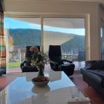 Wohnzimmer mit Sofa, Sessel und Blick auf Hügel.