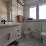 Badezimmer mit Waschbecken, Toilette, Bidet und Fenster.