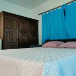Schlafzimmer mit Bett, Holzschrank und blauen Vorhängen.