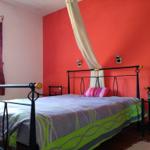 Schlafzimmer mit roter Wand, Metallbett und Vorhängen