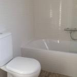 Badezimmer mit Badewanne, Toilette und Fliesenwand