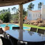 Terrasse mit Tisch und Stühlen, Pool und Garten im Hintergrund.