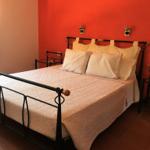 Schlafzimmer mit Bett, roter Wand und Fenster mit Vorhängen