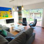 Wohnzimmer mit Sofa, Fernseher und Blick auf Terrasse