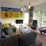Wohnzimmer mit Sofa, Fernseher und Blick auf Terrasse