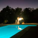 Beleuchteter Pool bei Nacht mit Steinformation und Bäumen im Hintergrund.