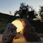 Eine leuchtende Kugel zwischen zwei Felsen im Garten bei Sonnenuntergang.