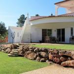 Eine Villa mit Pool, Terrasse und Steinmauer im Garten.