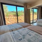 Schlafzimmer mit Doppelbett und Blick auf Steinmauer und Grünflächen.