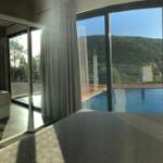 Schlafzimmer mit Blick auf Pool und Berglandschaft durch große Glasflächen.