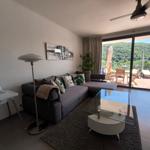 Wohnzimmer mit Sofa, Couchtisch und Blick auf Balkon mit Pool.