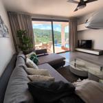 Wohnzimmer mit Sofa, Glas-Tisch und Blick auf Pool und Garten