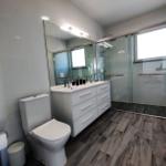 Badezimmer mit Dusche, Waschtisch und Toilette. Holzdielenboden und Spiegelschrank.