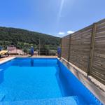 Pool mit Liegestühlen und Holzzaun. Berglandschaft im Hintergrund.