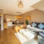 Wohn- und Essbereich mit Küche unter Dachschrägen. Holzboden, Sofa, Couchtisch und Pendelleuchten.