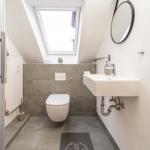 Badezimmer mit Dusche, Toilette und Waschbecken unter Dachschrägen.