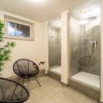 Badezimmer mit Dusche, Pflanze und zwei Stühlen.