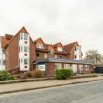 Rotes Backsteinhaus mit weißen Balkonen und Dachgauben an der Straße